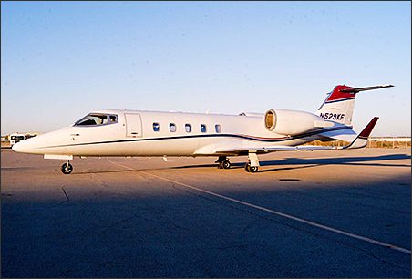 A white Learjet with red and blue accents, this Lear 60 used business jet is parked on an airport tarmac under a clear sky—an exceptional corporate aircraft for sale.