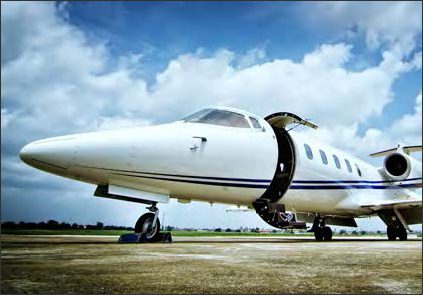 A used Lear 60 aircraft, a popular business jet, is parked on an airport runway with the door open under a partly cloudy sky, ready to offer premium general aviation services.
