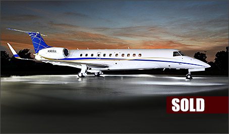 An Embraer Legacy 600 used business jet is parked on a runway at sunset, with a "SOLD" label in the bottom right corner.