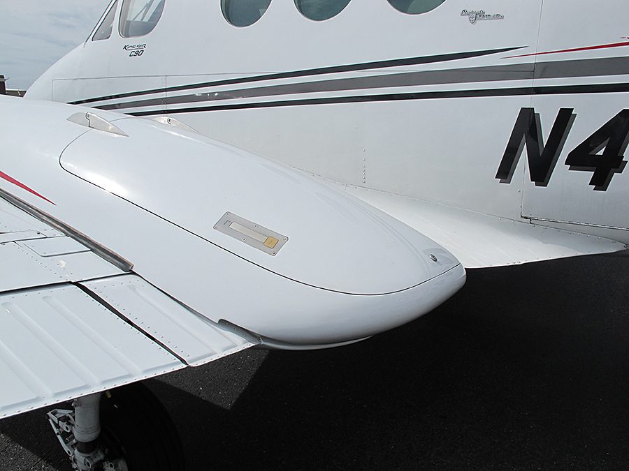 Close-up of the wing root and fuselage of a white twin-engine airplane, showing part of the wing, landing gear, and registration number "N4".