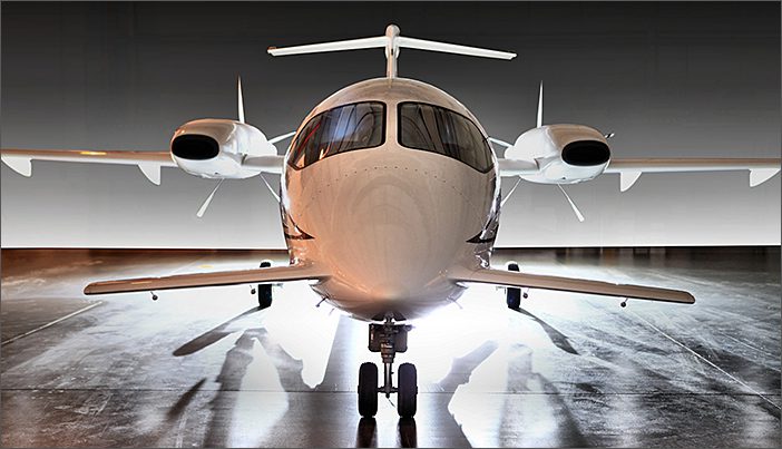 A 2005 Piaggio Avanti P190, a used turboprop aircraft, is parked indoors facing forward, its landing gear down and lights illuminating the floor beneath it. This sleek business jet has been SOLD after 1095 hours of use.