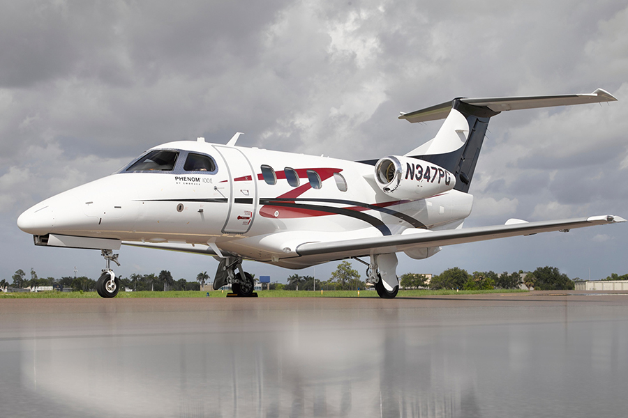 A white and black Phenom 100E business jet parked on an airport tarmac, representing options similar to a Phenom 100E for sale.